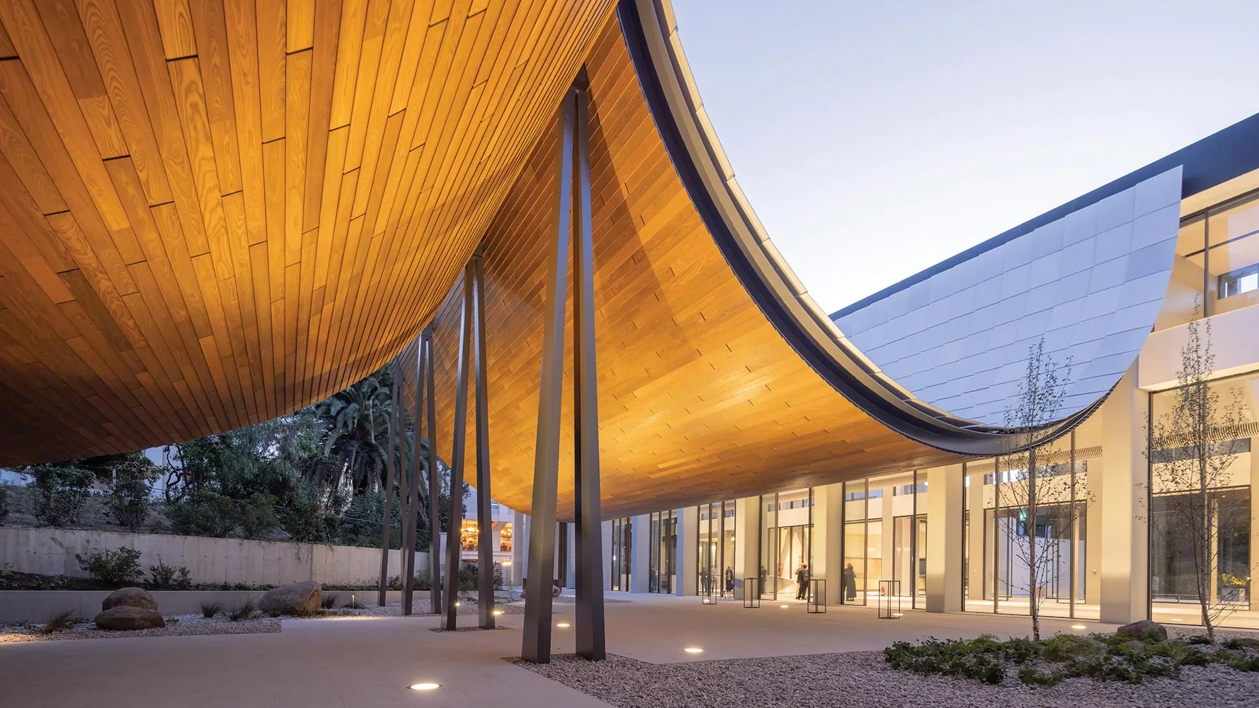 Sleek modern building in Milan with sweeping wooden canopy roof and glass façades blending contemporary and natural design.