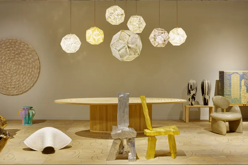 Exhibition with modular metallic structures, flooring, and eclectic design pieces.