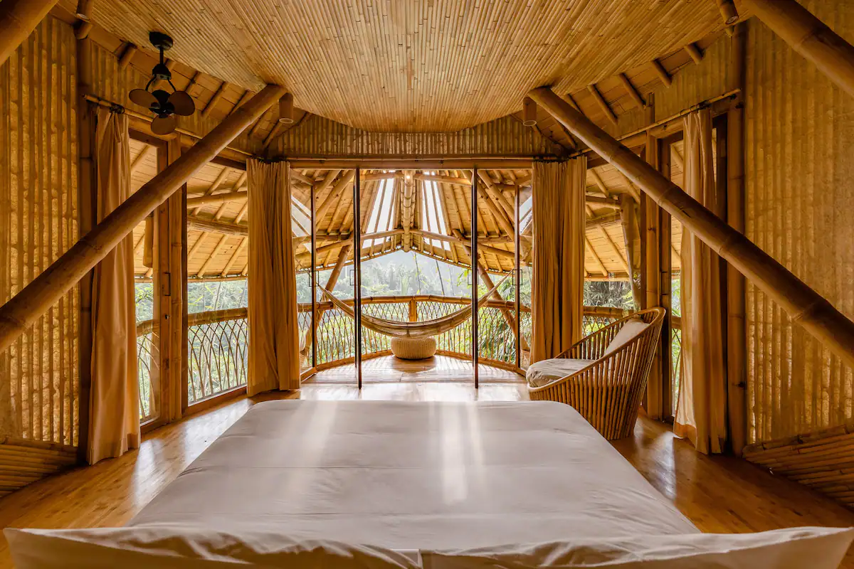 Luxury bamboo villa bedroom in Bali with natural textures, open design, and panoramic views of tropical greenery.