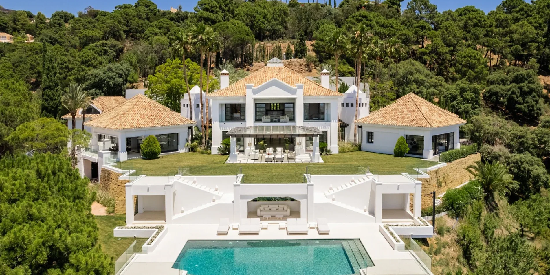 “Contemporary Mediterranean villa with private pool, palm trees, and illuminated terrace at dusk