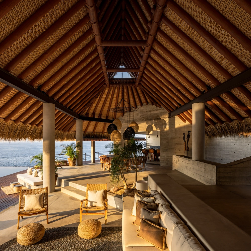 Open-air coastal villa featuring thatched roof design inspired by African vernacular architecture and natural materials