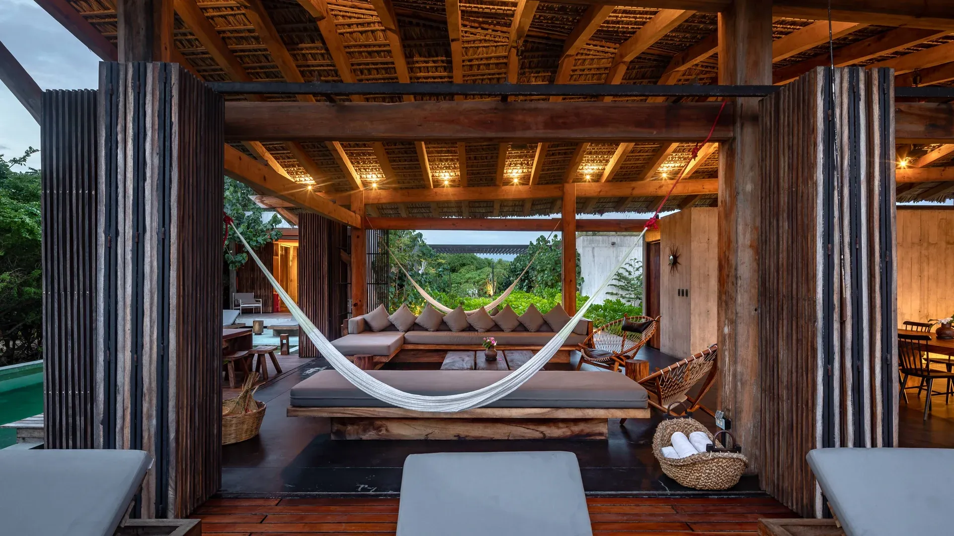 Bohemian luxury villa in Tulum featuring open wooden architecture, hammocks, and jungle surroundings.
