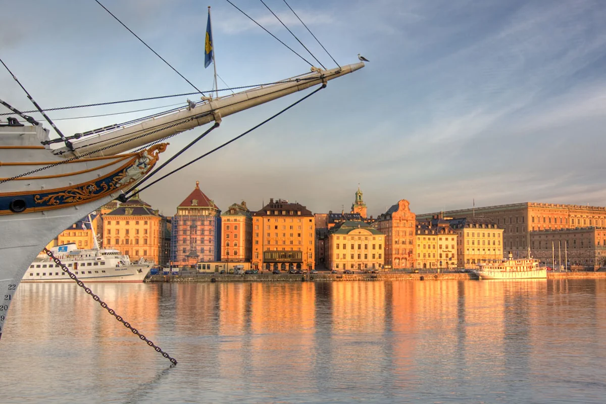 Historic buildings along Skeppsbron quay in Stockholm reflecting golden evening light on the water.