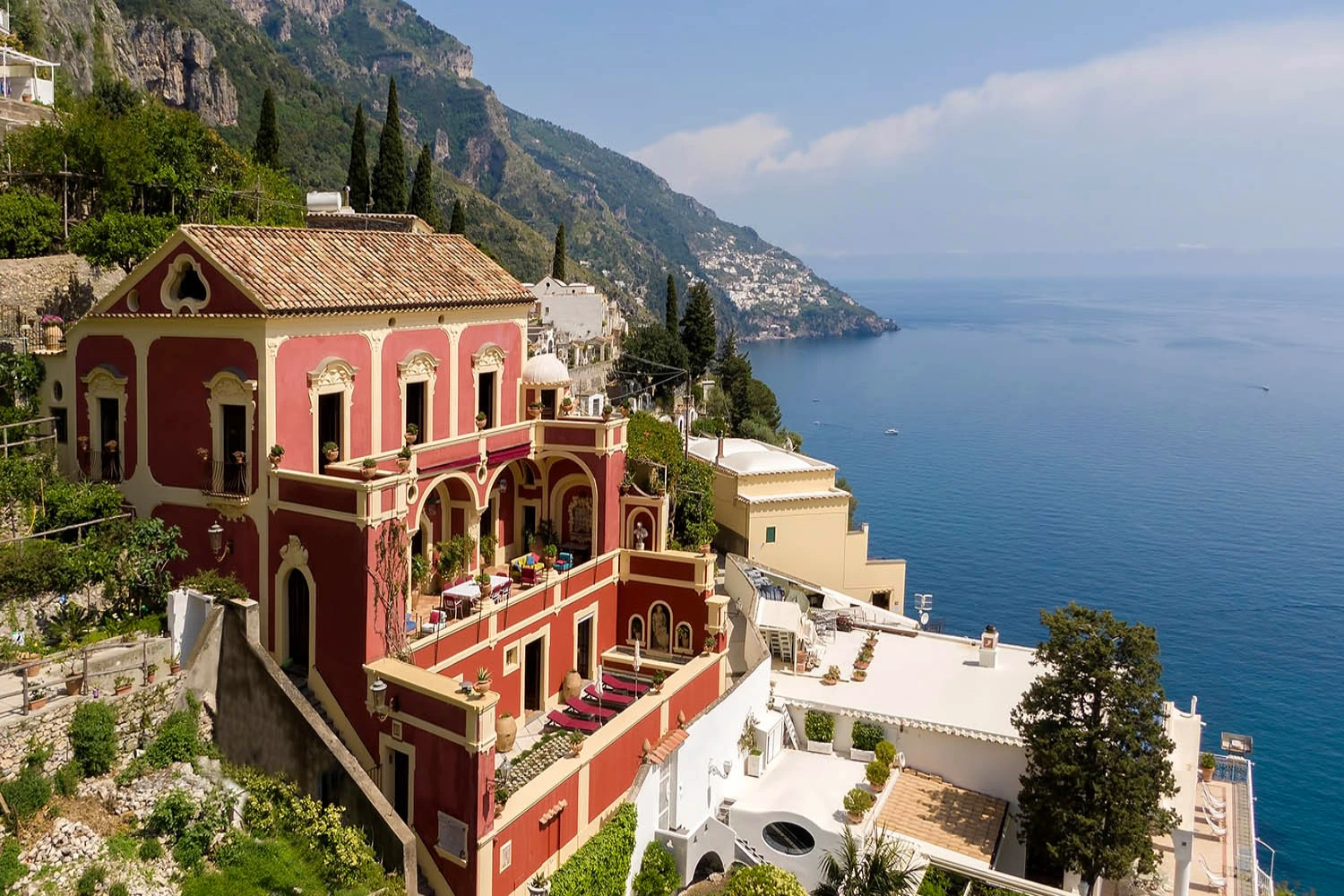 Historic red palazzo perched above the Amalfi Coast, featuring ornate balconies and panoramic sea views — an iconic example of Italian baroque coastal architecture.