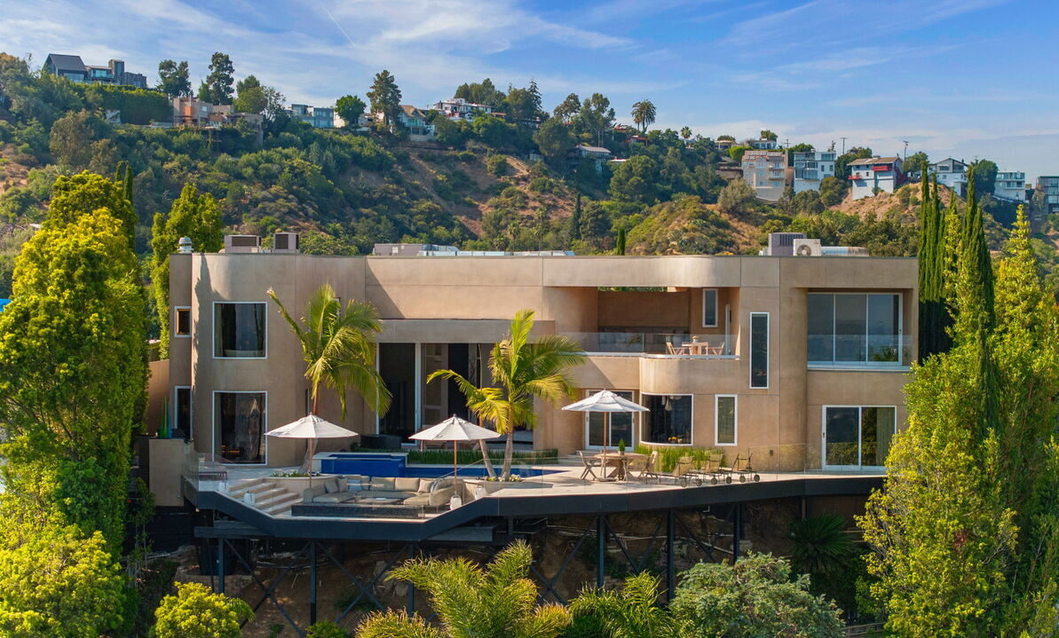 Elegant Spanish Revival mansion in Beverly Hills with white stucco walls, terracotta roof tiles, and landscaped courtyard.
