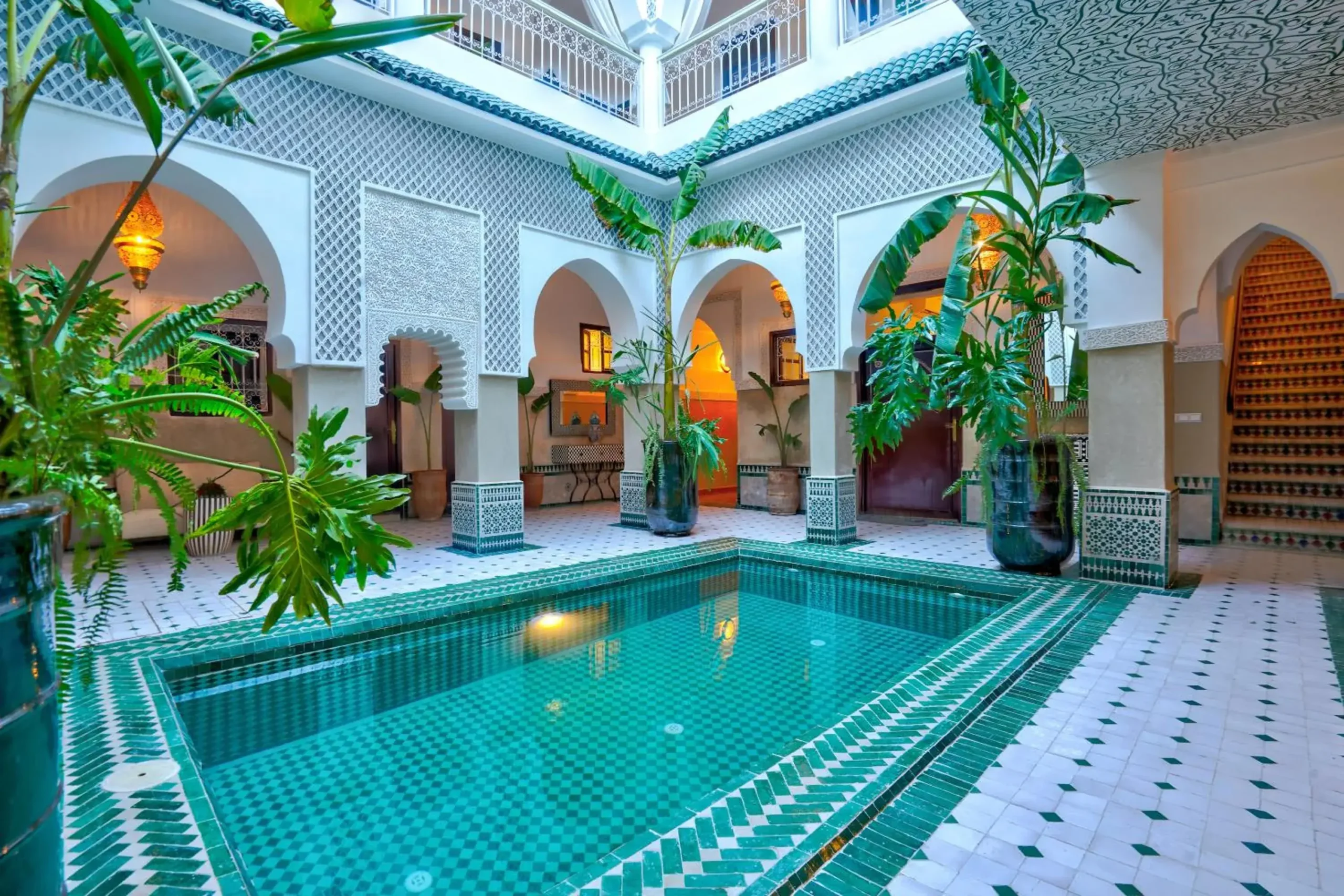 Luxurious Moroccan riad courtyard with carved stucco arches, marble floors, and central plunge pool