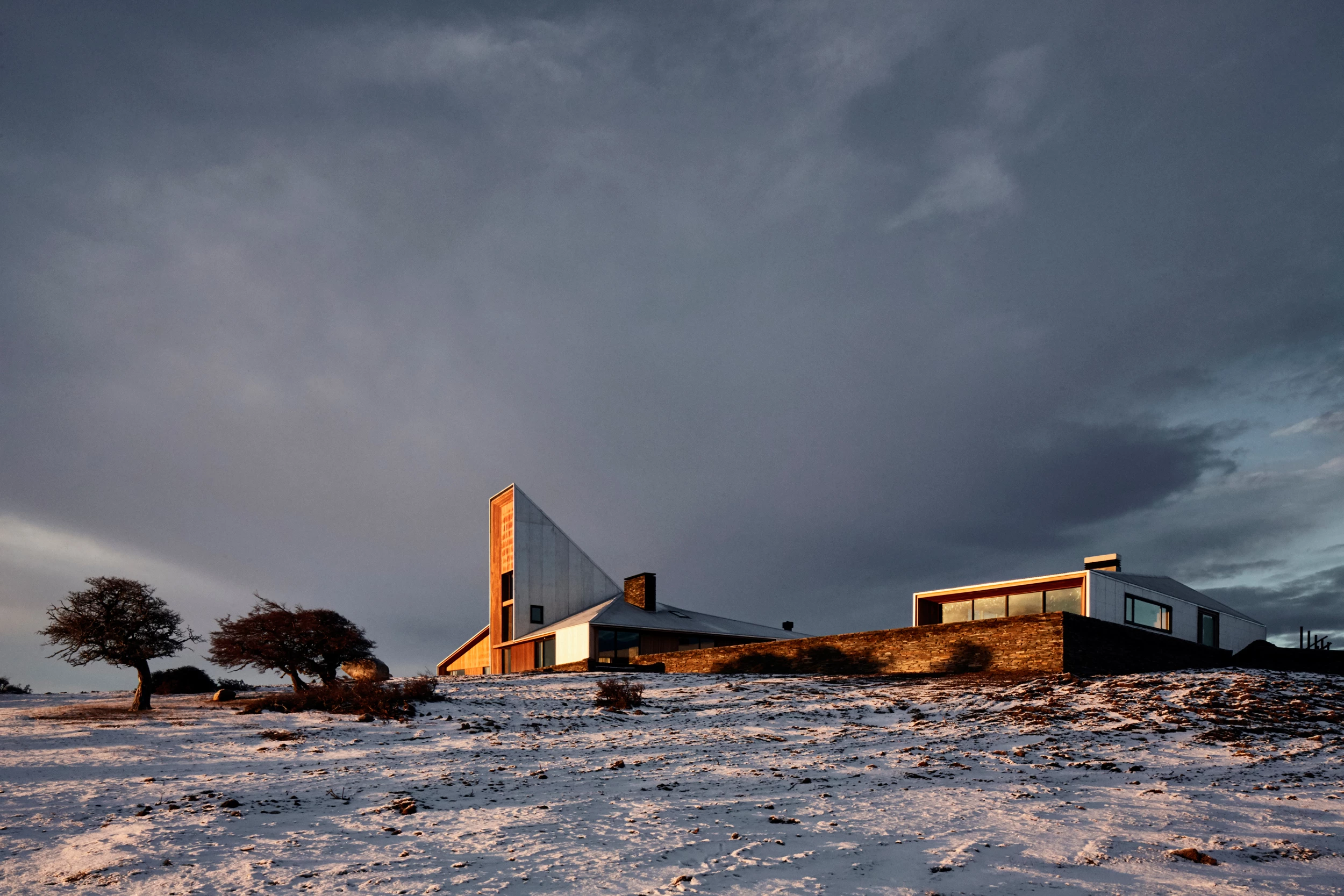 Modern house surrounded by snow-covered landscape at sunset — a striking example of contemporary architecture integrated with the wild beauty of southern Argentina.
