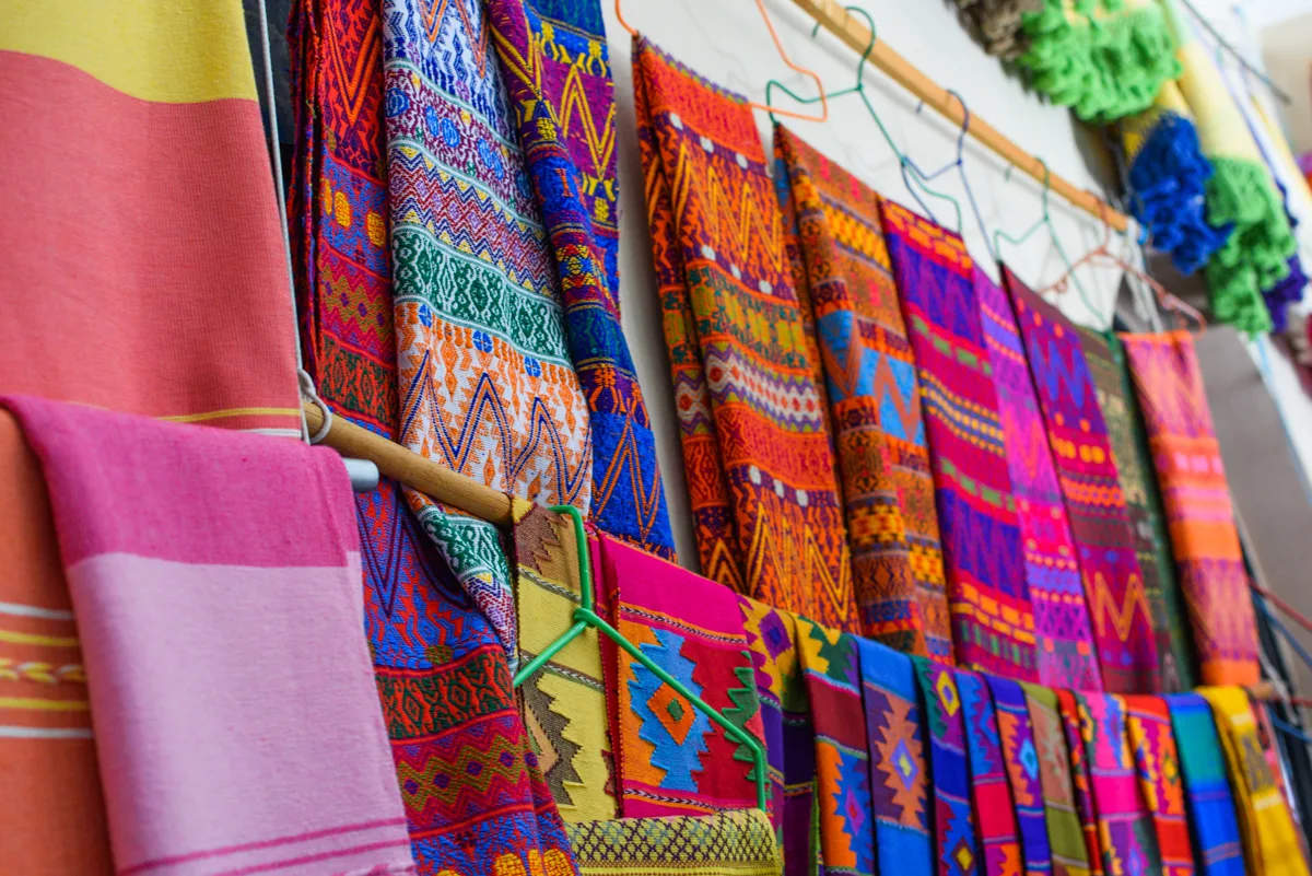 “Colorful handwoven Oaxacan textiles with intricate geometric patterns displayed in a traditional market.