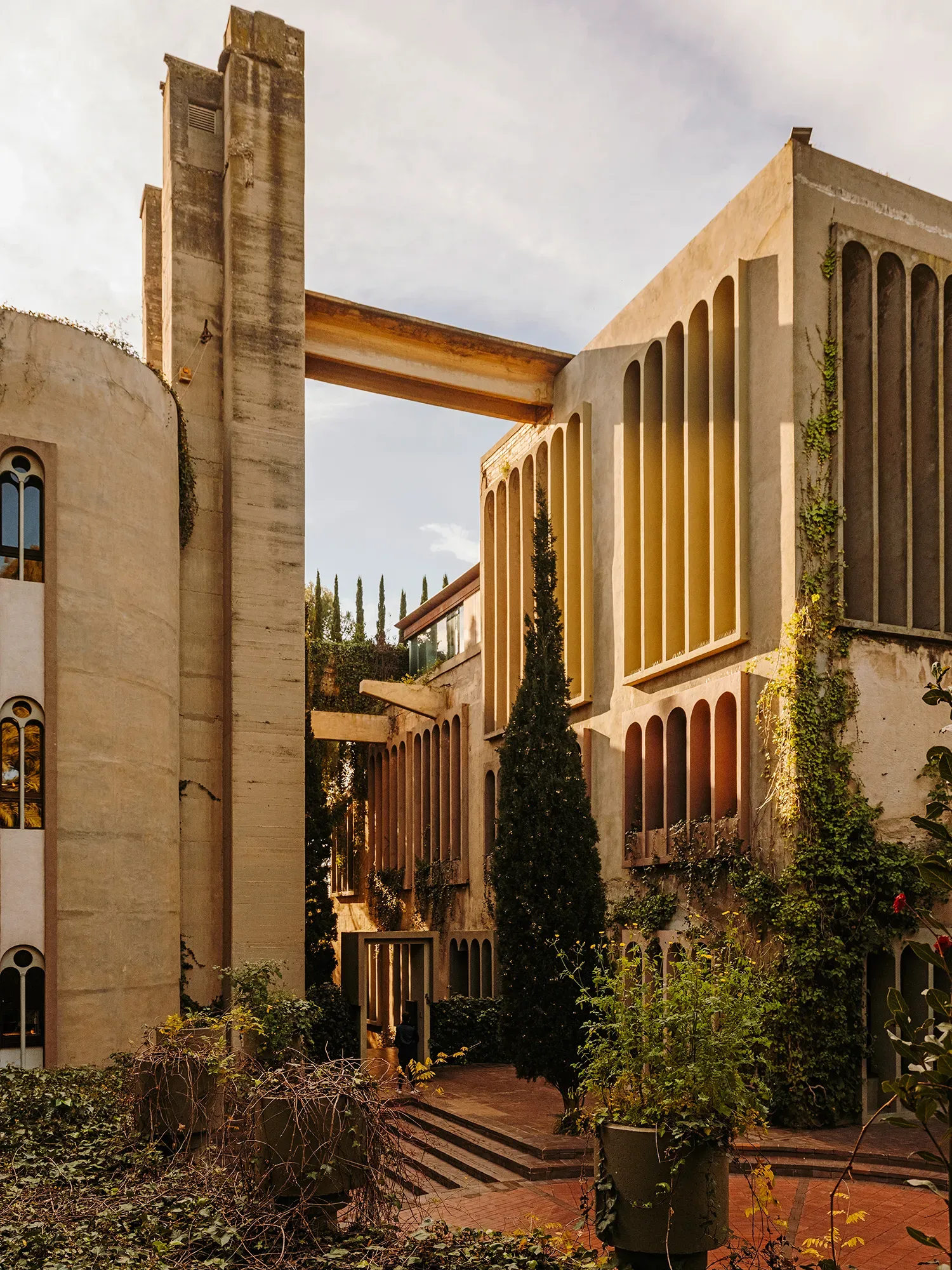 Exterior view of La Fábrica by Ricardo Bofill, a converted cement factory blending Brutalist architecture with vegetation.