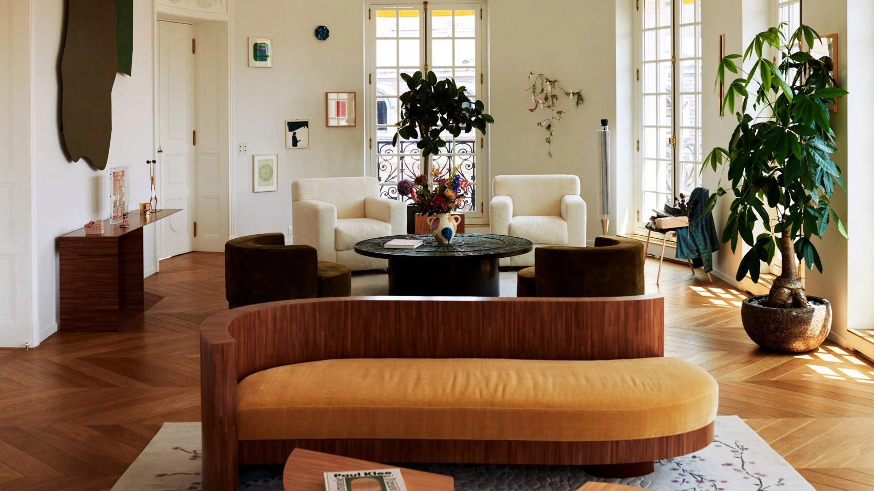 Luxury Haussmannian apartment interior in Paris featuring restored classical moldings, herringbone parquet flooring, sculptural contemporary furniture, and material-driven modern design.