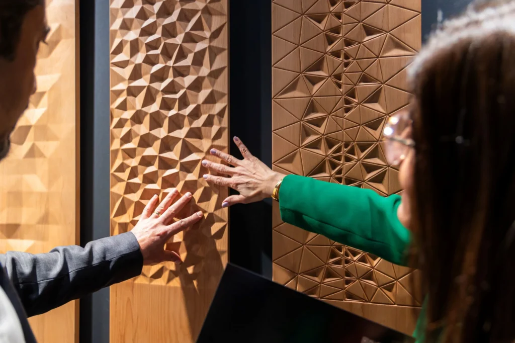 Visitors exploring sculptural wood wall panels at INDEX Saudi Arabia 2025, showcasing material craftsmanship and contemporary interior design innovation.