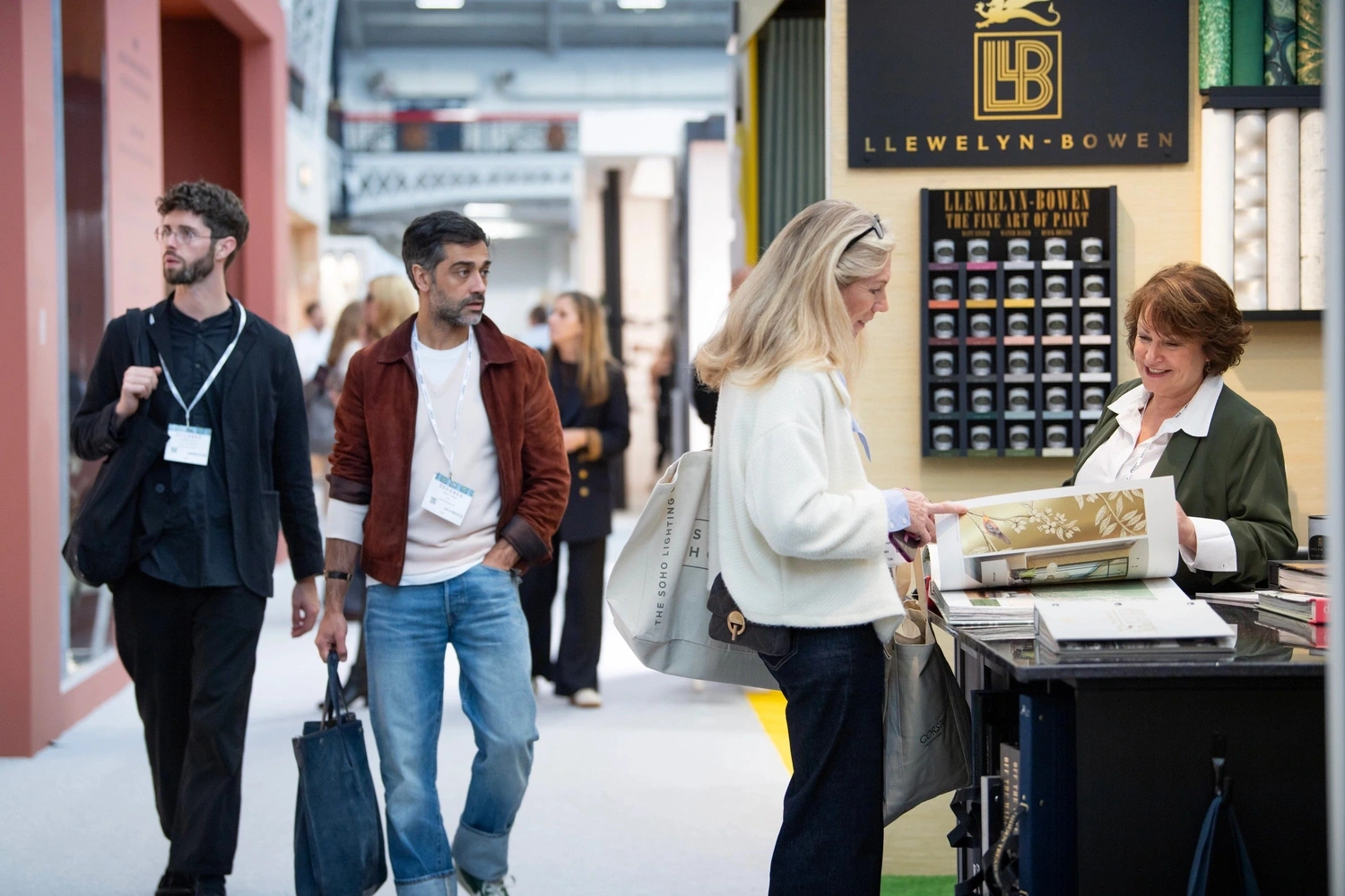 Visitors explore the Llewelyn‑Bowen stand at Decorex 2025, Olympia London. The booth showcases “The Fine Art of Paint” collection with elegant displays of color samples and wallpaper rolls, capturing the fair’s vibrant atmosphere of design innovation.