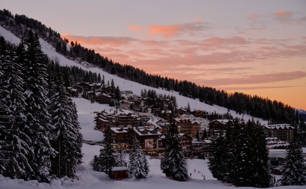 Snow covered Courchevel mountain resort at sunset, surrounded by pine forests near Aman Le Mélézin in France.
