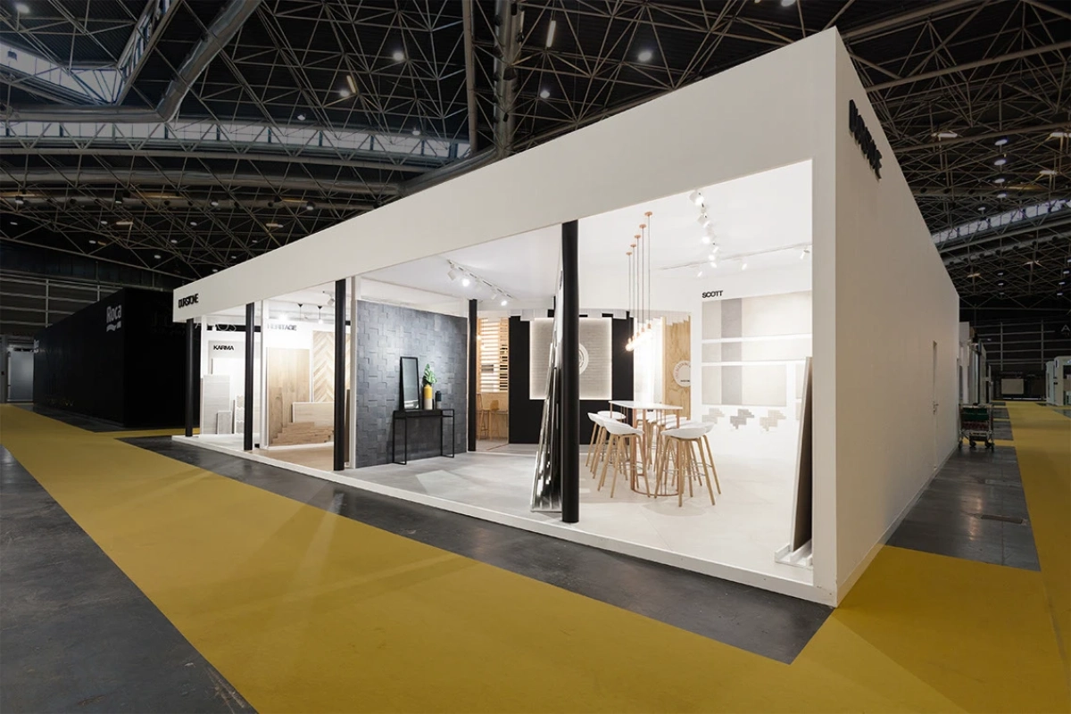 Durstone’s stand at Cevisama 2017, featuring an open white structure, black columns, textured tile displays, and wooden bar stools.
