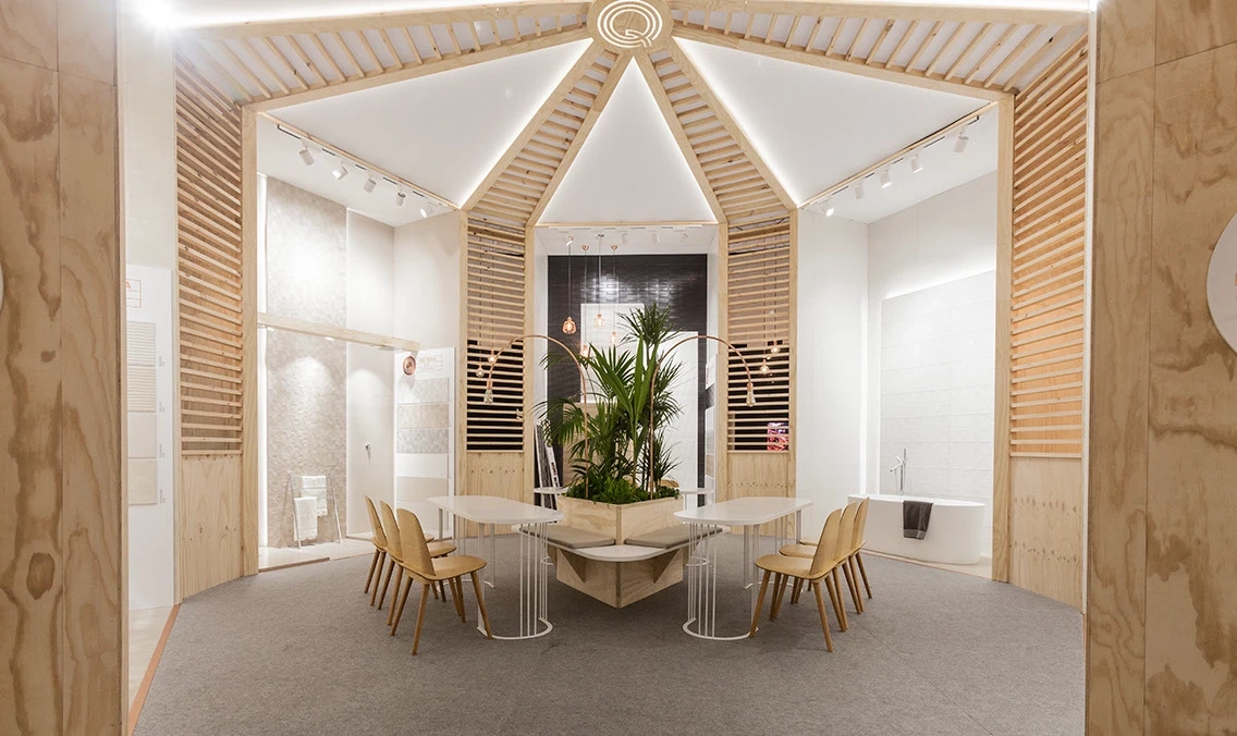 Interior of Durstone’s Cevisama 2017 stand, with radial wooden slats, ceramic wall displays, and seating around a central planter.