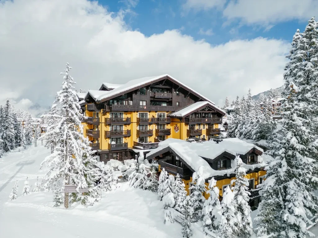 Cheval Blanc Courchevel surrounded by snow-covered pine trees and ski slopes in Courchevel 1850, France.