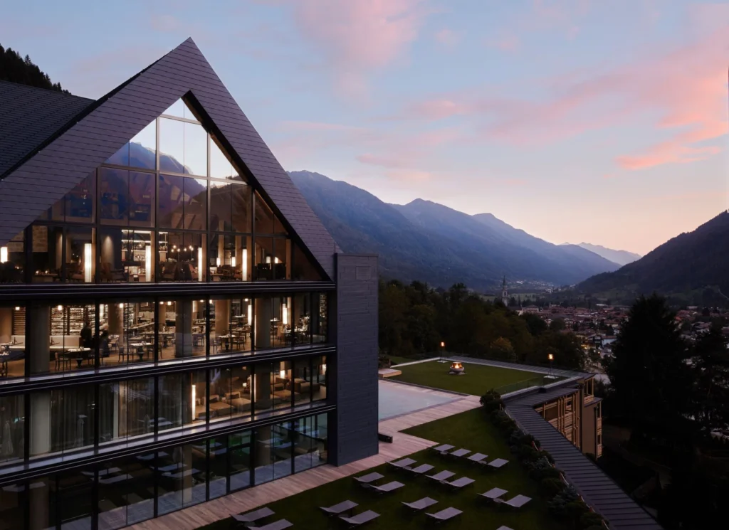 Lefay Resort & SPA Dolomiti at sunset, featuring contemporary mountain architecture, expansive glass façades and views across the Dolomites in Italy.