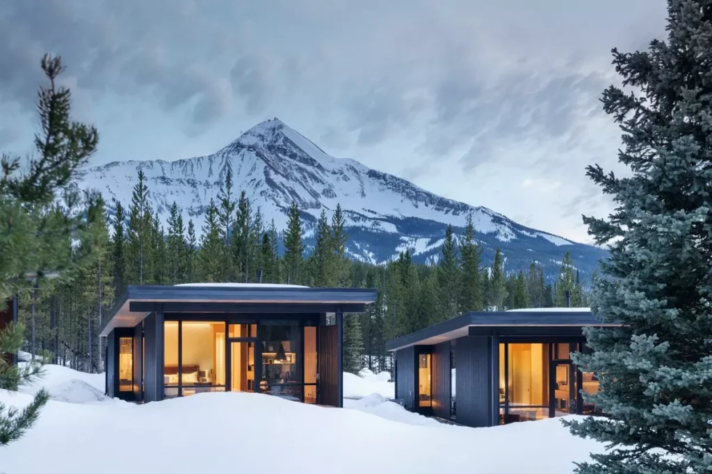 One&Only Moonlight Basin luxury cabins surrounded by snow-covered pine forest with dramatic mountain views in Montana, United States.
