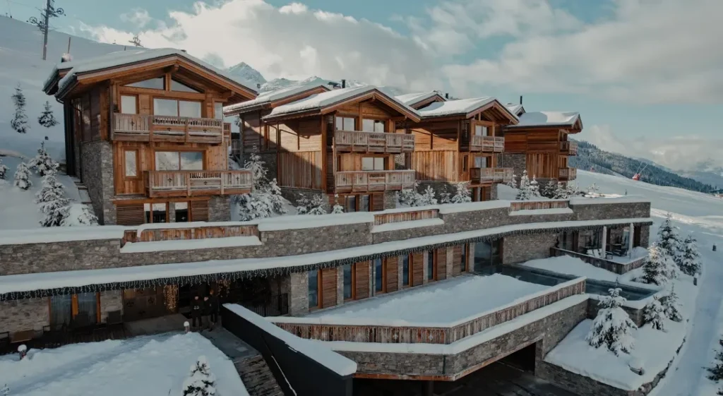 Ultima Hotel Courchevel luxury chalets with timber and stone façades surrounded by snow covered ski slopes in Courchevel, France.