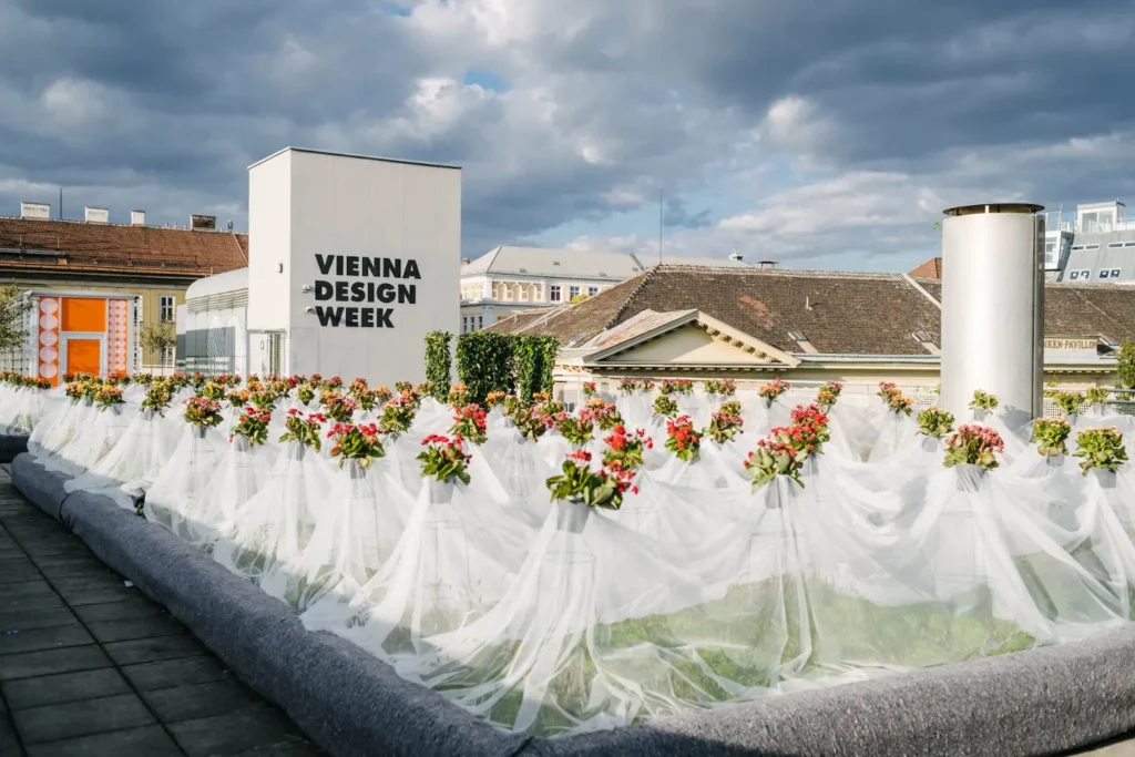 Floral design installation surrounding Vienna Design Week signage against the architectural skyline of Vienna.